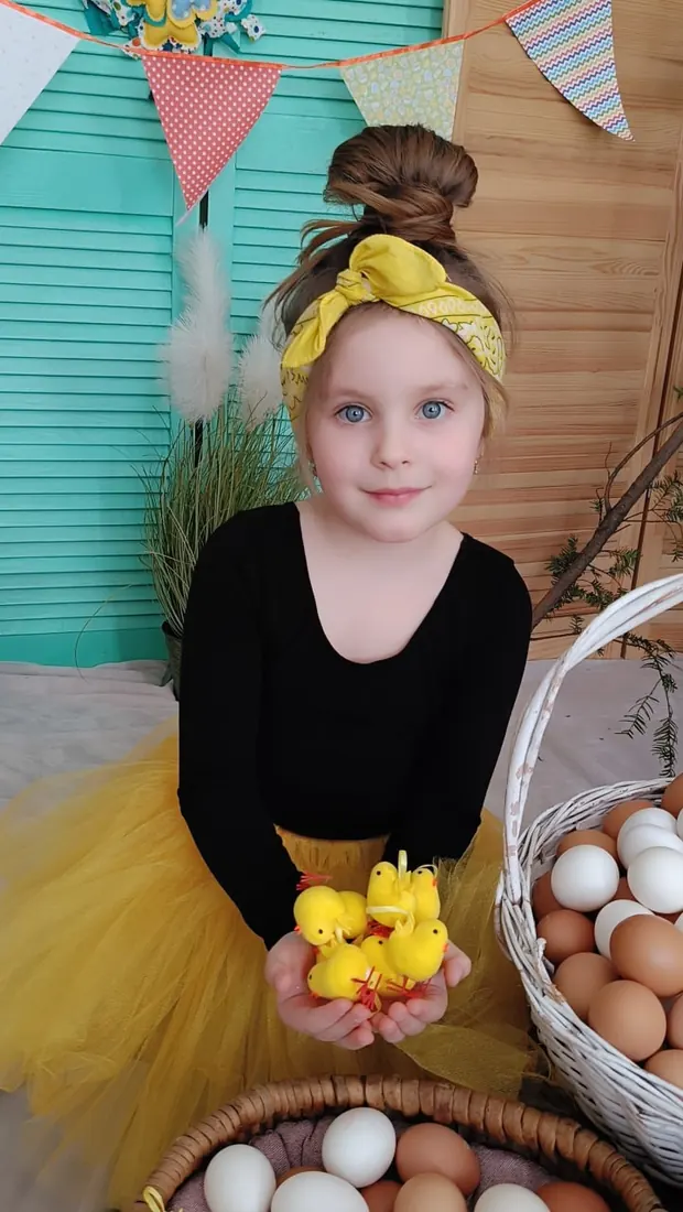Дівчинка з іграшковими курчатами у великодній фотозоні